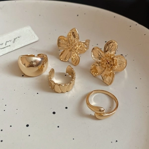 Detailed set of five gold floral and geometric rings on a decorative ceramic plate