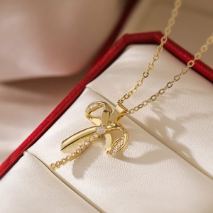 Elegant gold-plated bow pendant necklace featuring sparkling cubic zirconia on a white box