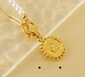 Detailed close-up of stainless steel OT buckle and embossed letter C pendant necklace