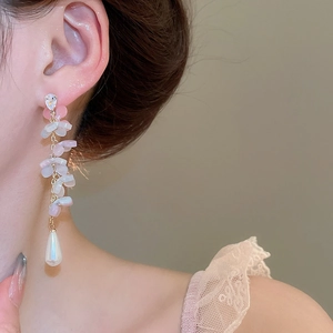 Close-up of dangling flower earrings with water drop pearls on a model
