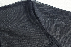 Detail view of sheer black mesh fabric with fine micro-holes and soft textured pleats