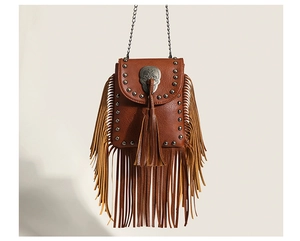 Detail of brown fringe crossbody bag with metal skull ornament and silver stud rivets