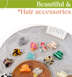 Assorted colorful cellulose acetate hair claw clips displayed on a rustic wooden tray
