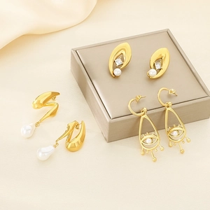 Détail de boucles d'oreilles œil et perles dorées avec zircon sur tissu en soie