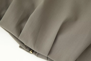 Detailed macro view of the taupe bomber jacket featuring high-quality metal zipper and seams
