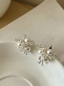 Artistic cluster pearl earrings on white ceramic rim showing organic metallic silver finish