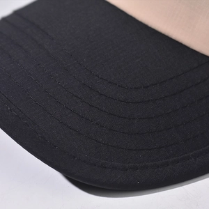 Macro detail of twill fabric stitching on a two-tone khaki and black short brim cap