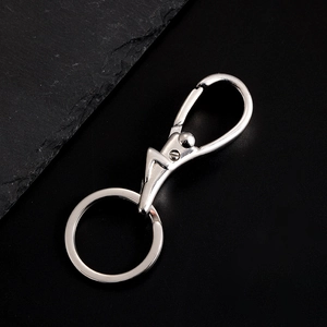 Close-up of polished stainless steel keychain carabiner with spring mechanism on dark stone