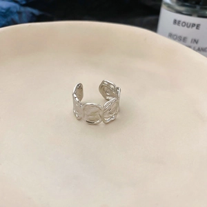 Macro detail of silver adjustable open ring with embossed rose floral texture patterns