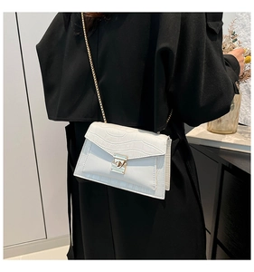 Close-up of white crocodile pattern crossbody bag with gold chain strap and buckle