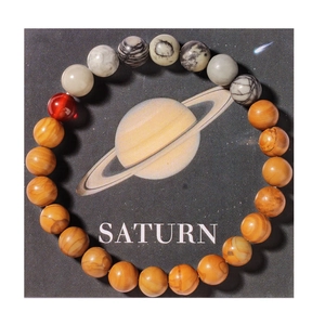Detail view of the Saturn planet themed natural stone bracelet on a black display card