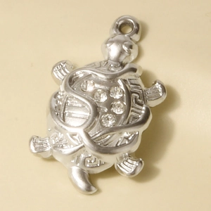Macro shot of silver stainless steel turtle pendant with sparkling rhinestone details