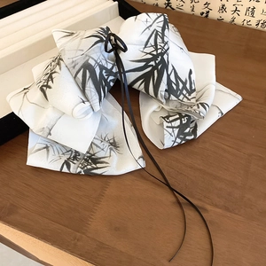 Detail of white satin bow hair claw clip with black ink bamboo painting on wooden desk