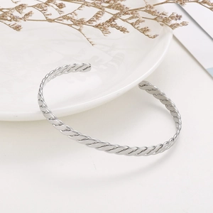 Vue détaillée de la texture torsadée argentée sur un bracelet jonc en acier inoxydable en C