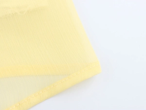 Vue macro du tissu en mousseline jaune clair montrant la texture et les coutures nettes