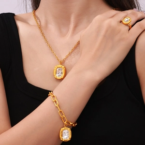 Gold-toned titanium jewelry set featuring crystal-inlaid oval plaques on a model