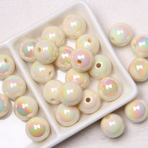 Macro shot of 16mm beige acrylic iridescent beads with center holes on ceramic plate