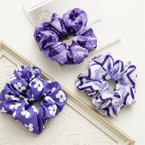Three purple fabric scrunchies with floral, plaid, and wavy patterns in a set
