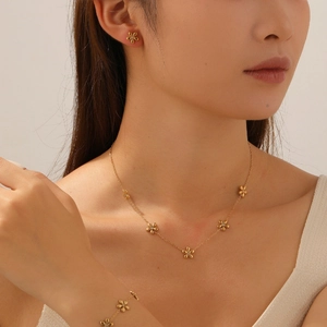 Detailed view of a gold plated stainless steel floral jewelry set on a model skin