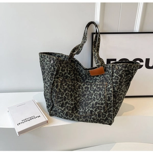 Detail of leopard print canvas tote bag featuring metal rivets and leather brand patch