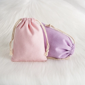 Close-up of pink and purple textured cotton linen drawstring pouches on white fur