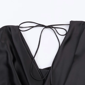 Close-up of black satin dress featuring a delicate lace-up neck design with smooth texture