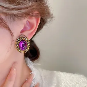 French retro gold earrings with purple oval gems and pearls on a female model