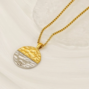 Minimalist round hammered gold and silver necklace with dual-tone texture on white fabric