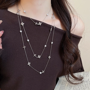 Close-up of layered silver necklace with flower and star pendants on a fashion model