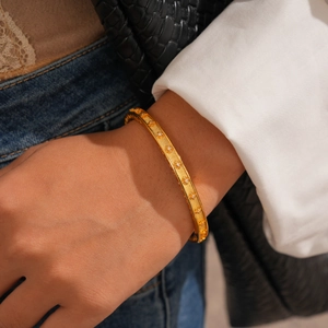 Gros plan sur un bracelet jonc plaqué or 24K avec motifs d'étoiles sur un poignet