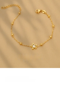 Detail of gold star bracelet with zircon inlay on luxury champagne silk background
