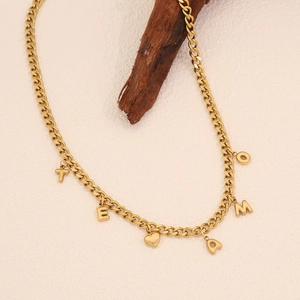 Collier maille cubaine dorée avec lettres TE AMO et pendentif cœur sur fond beige