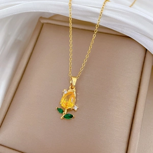 Detailed close-up of champagne gold rose pendant with yellow teardrop gem and green leaves