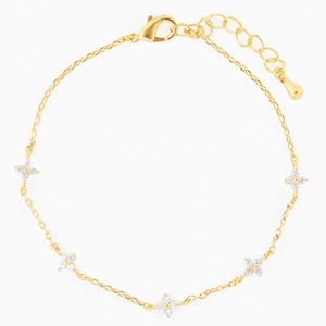 Close-up of elegant gold chain bracelet featuring five sparkling zircon clover charms