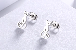 Macro shot of silver-colored hollow cat earrings with butterfly backs on a white surface
