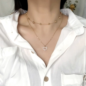 Detail of layered gold snake bone necklace with heart pendant and metallic beads