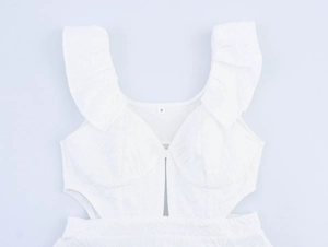 Close-up of white dress bodice with ruffled straps, cutout details and crinkle fabric