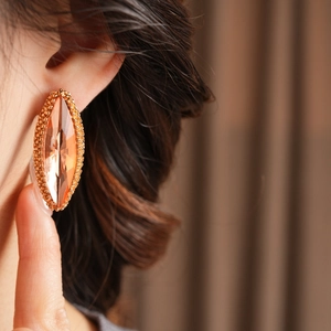 Close-up of a marquise-cut champagne crystal earring with gold beaded border worn by a model