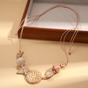 Detail of bohemian necklace featuring woven rattan disk and geometric wooden beads charms