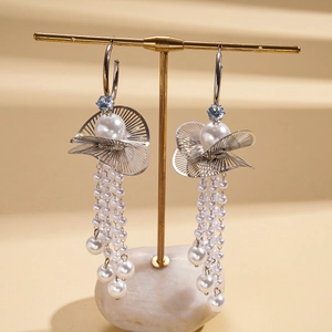 Detail of C-shaped leaf earring with hanging pearl tassels and blue zircon stud