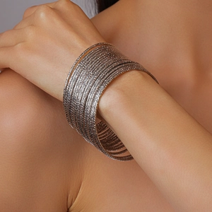 Dettaglio di un set di 20 bracciali rigidi sovrapposti in argento con trama martellata