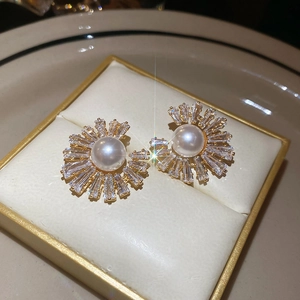 Macro shot of gold-plated flower stud earring with central pearl and zircon petals