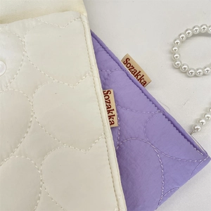 Close-up of quilted heart fabric pouches in cream and lilac with pearl chain accents