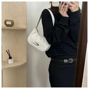 Close-up of a white crescent shoulder bag with a unique silver metal buckle detail