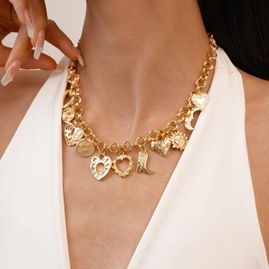 Close-up of gold chain necklace with sun, moon, heart, and cowboy boot charms on model