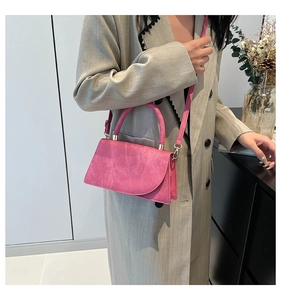 Close-up of pink crossbody bag with gold hardware shown on a model for scale and style