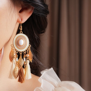 Macro shot of vintage enamel earring with leaf details and fringe tassels on model