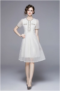 Close-up of elegant French lace dress featuring black-gold braided trim and pearl buttons