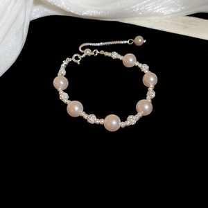 Detail of elegant pearl bracelet with silver hollow beads on black velvet backdrop