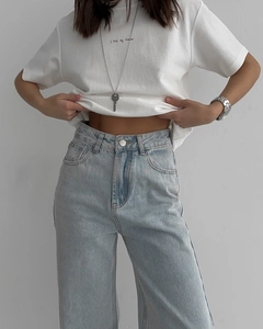 Détail du pantalon en jean délavé bleu clair avec taille haute et bouton métallique